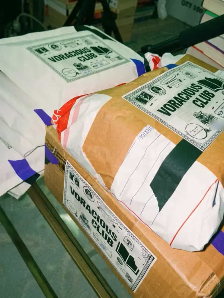 A box and a wrapped parcel, each with a large Voracious Club label, beside white mailers