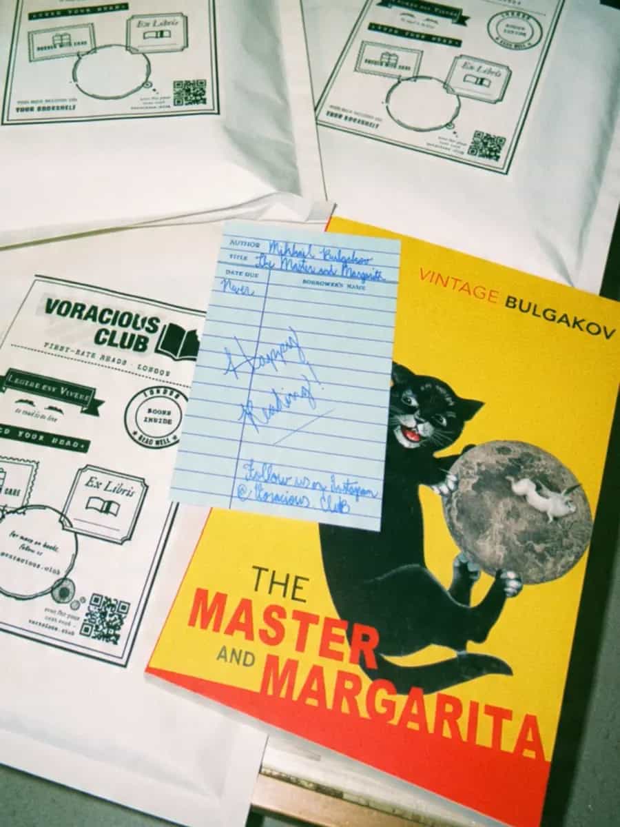The Master and Margarita with a handwritten library-card note saying Happy Reading, next to Voracious Club mailers