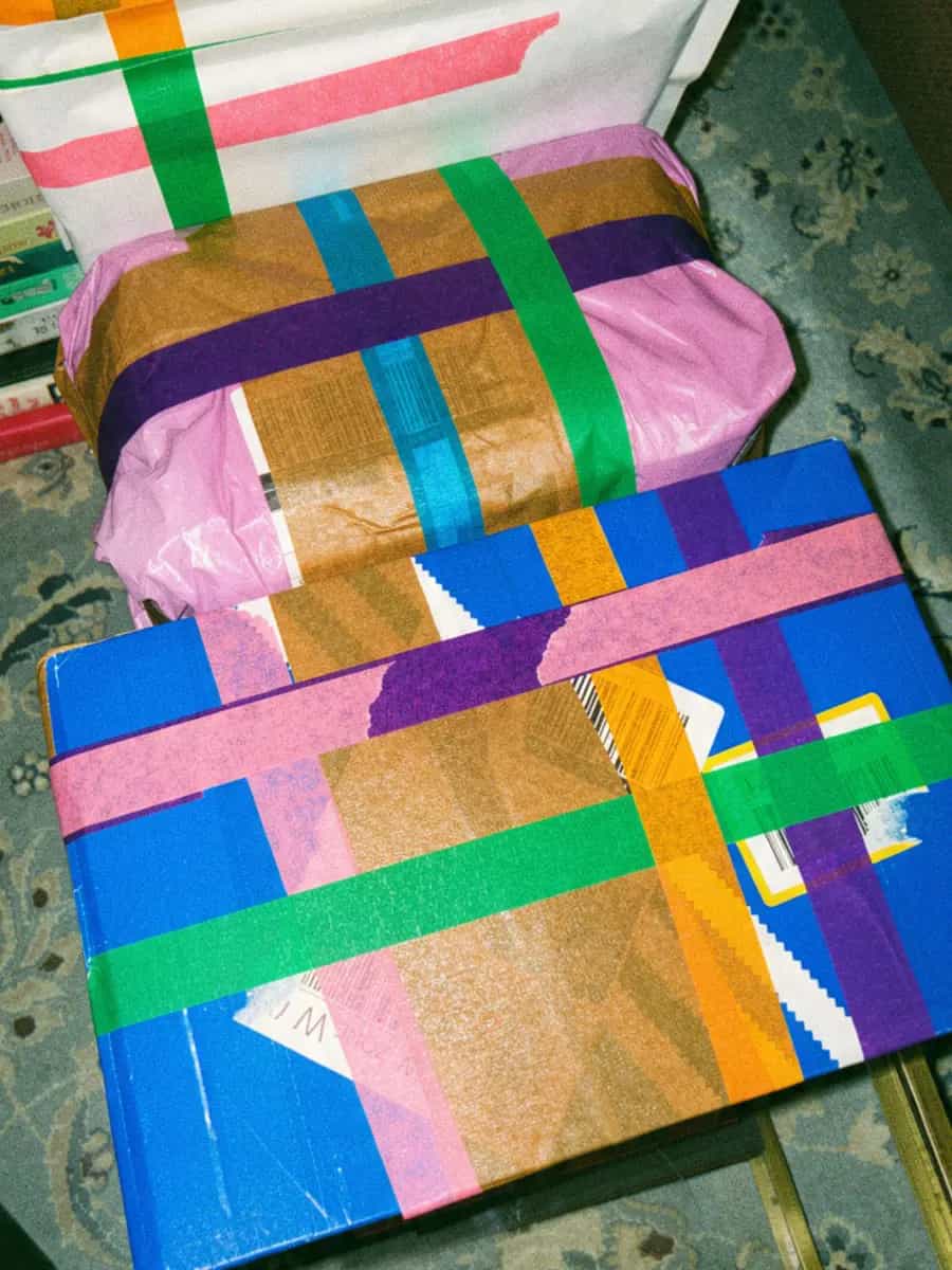 Book parcels criss-crossed with pink, green, orange, blue and purple tape on a glass table