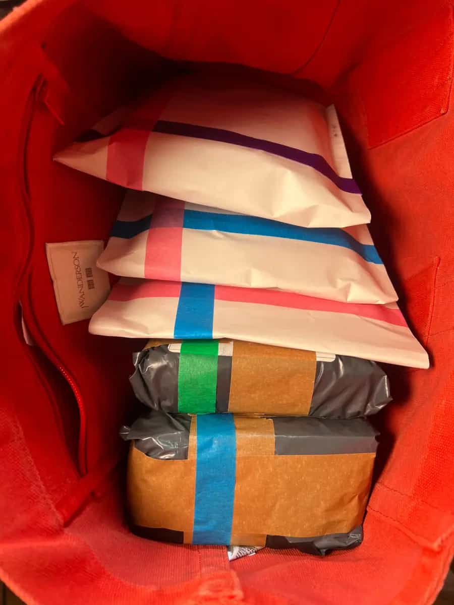 A red tote bag packed with parcels wrapped in white paper with pink and blue tape